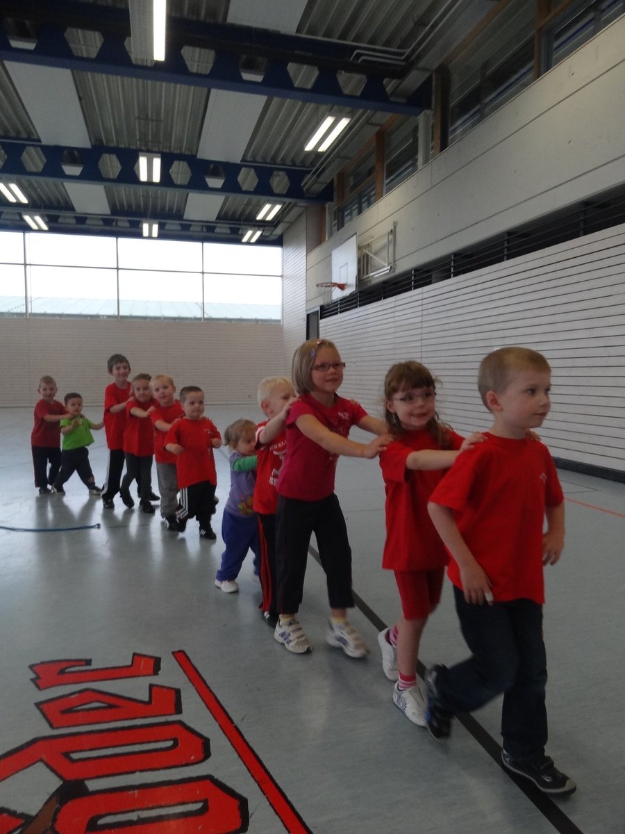 Kinder laufen in einer Reihe durch die Turnhalle