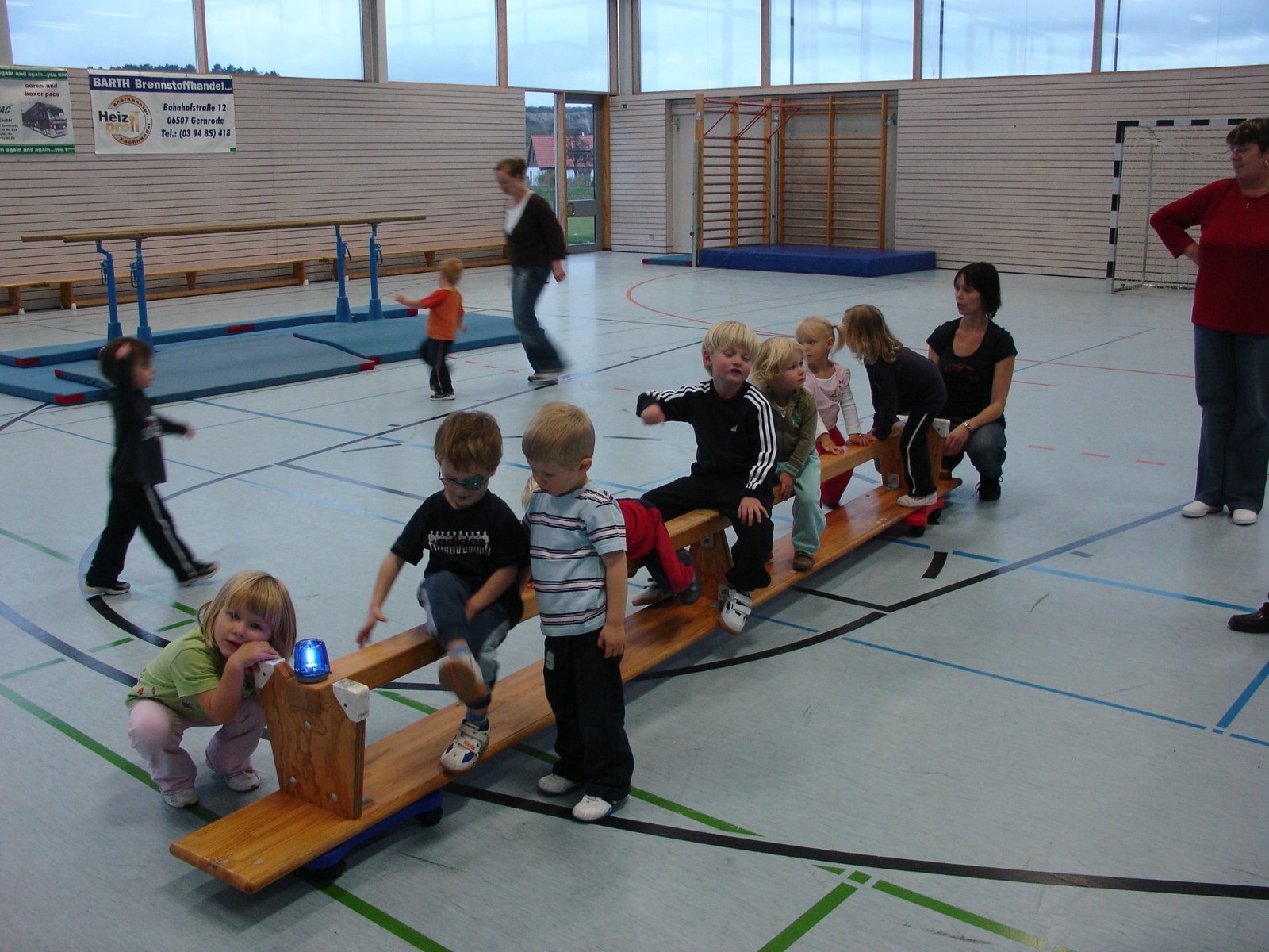Kinder sitzen und spielen auf einer Turnbank