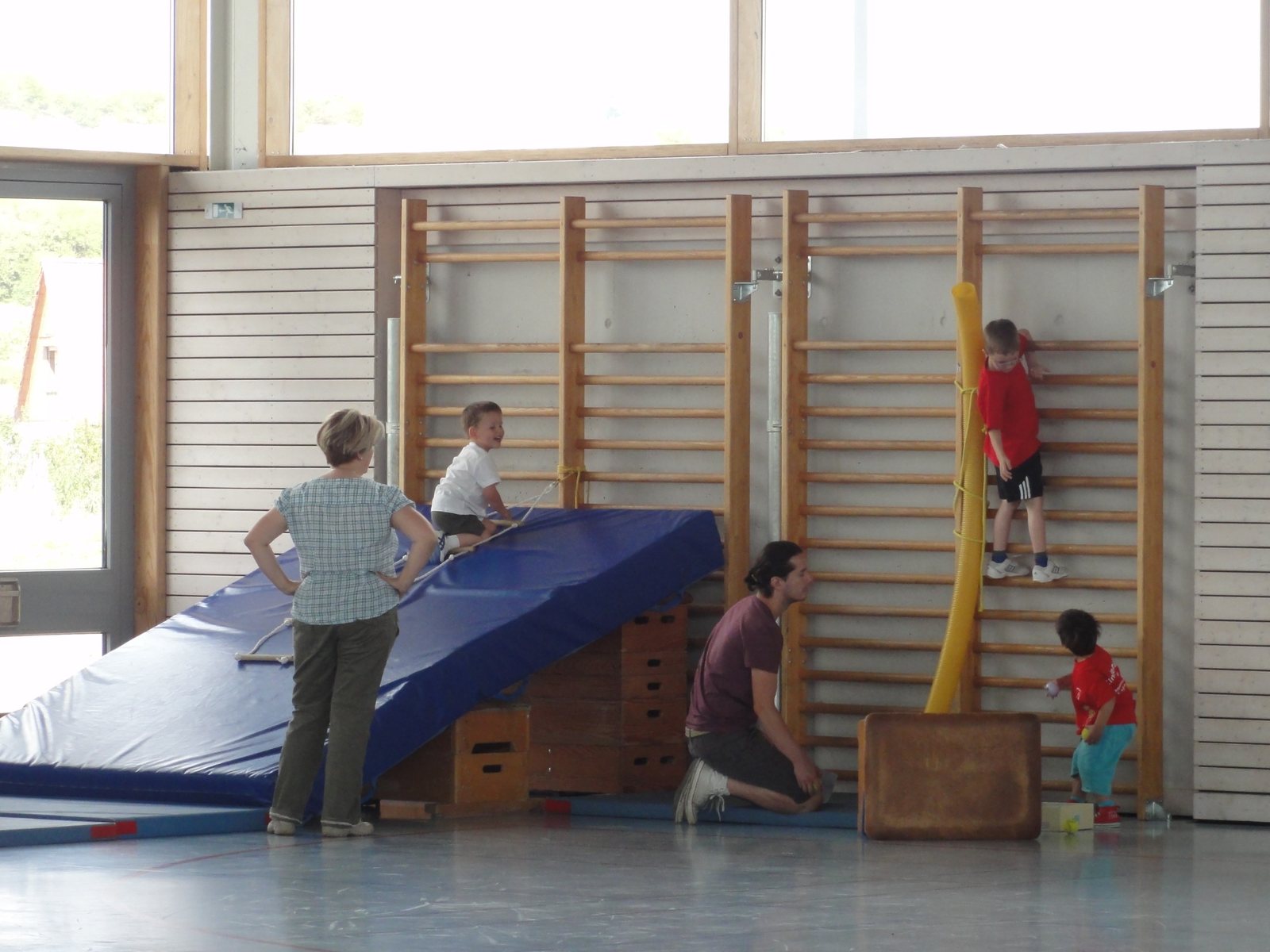 Kinder turnen an der Sprossenwand und an Matten
