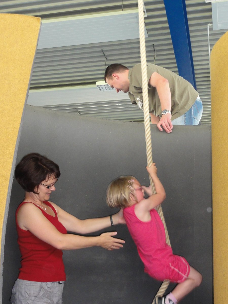 Kind klettert am Seil mit Hilfestellung